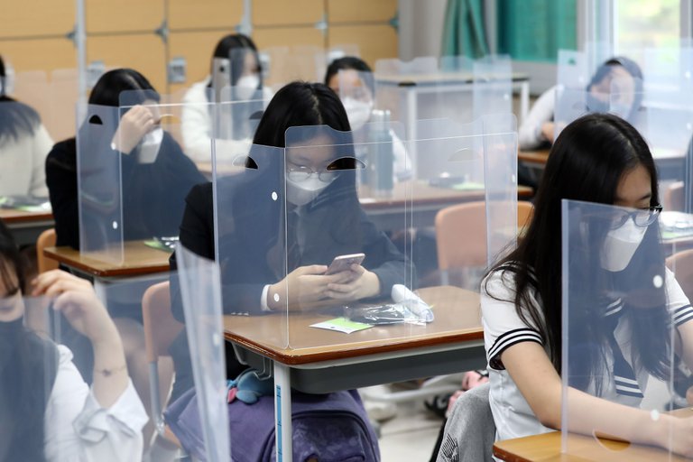 Los estudiantes esperan que la clase comience con paneles de plástico colocados en sus escritorios en la Escuela Secundaria Jeonmin en Daejeon, Corea del Sur. EFE/EPA/YONHAP